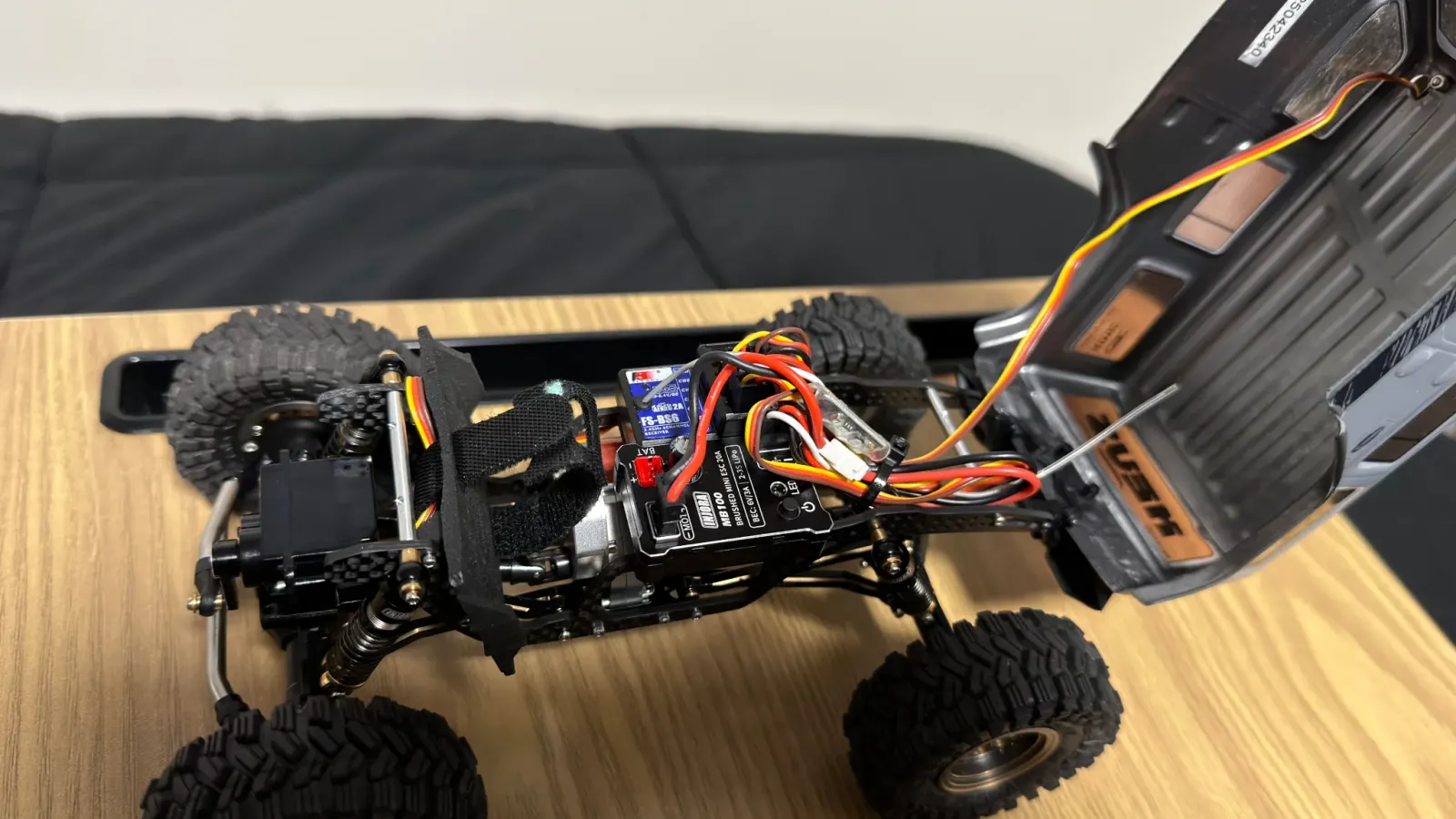 SCX24 chassis with the body flipped up, showing the ESC, receiver, and wiring