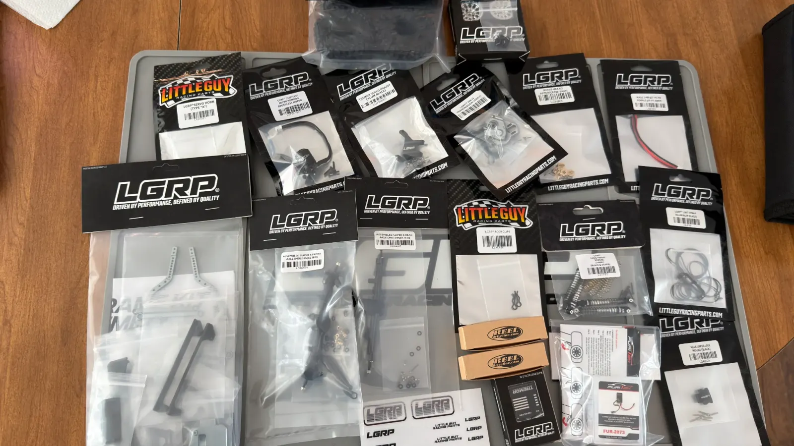 A haul of Little Guy Racing Parts packages laid out before a build