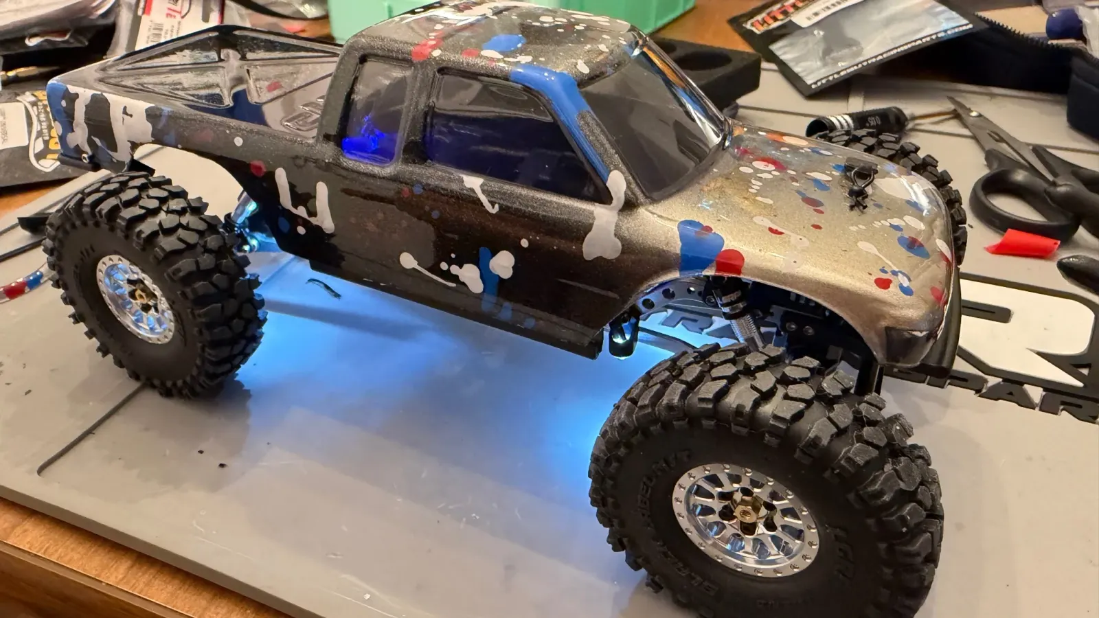 A custom painted SCX24 lit up with blue underglow LEDs