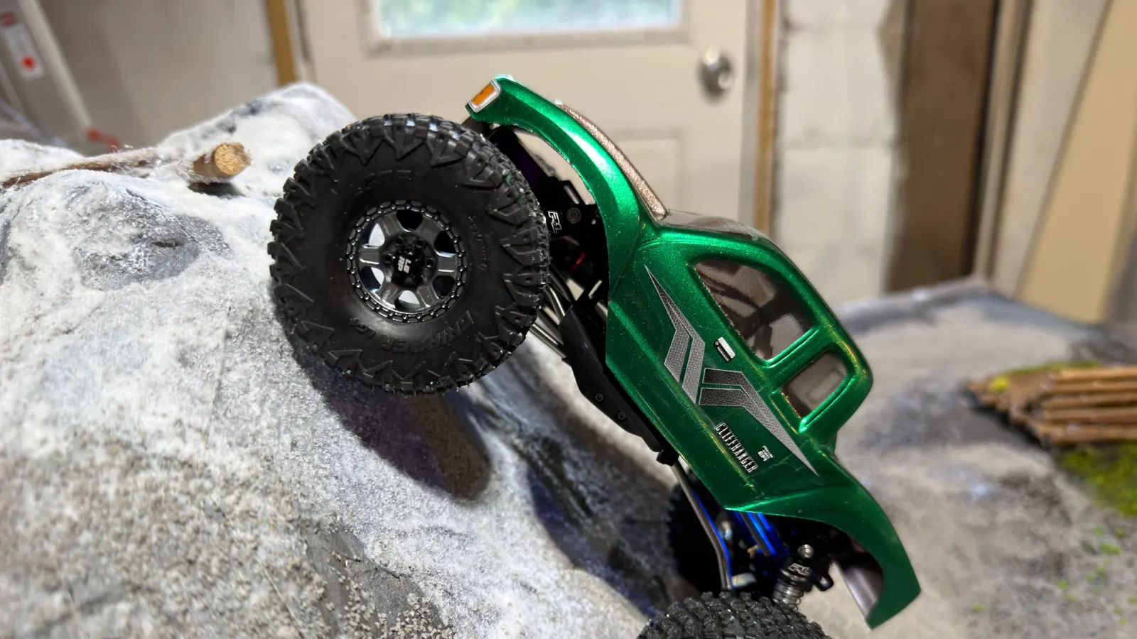 A green SCX24 climbing a near vertical rock face
